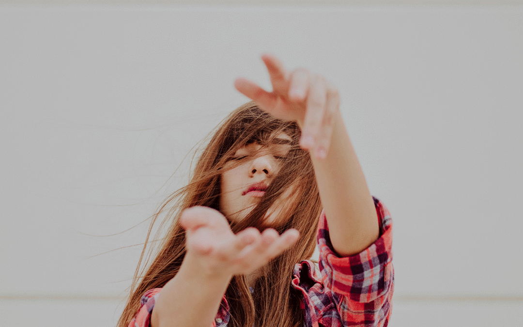 A woman with dark hair and a red and black plaid shirt holds her arms forward in surrender.